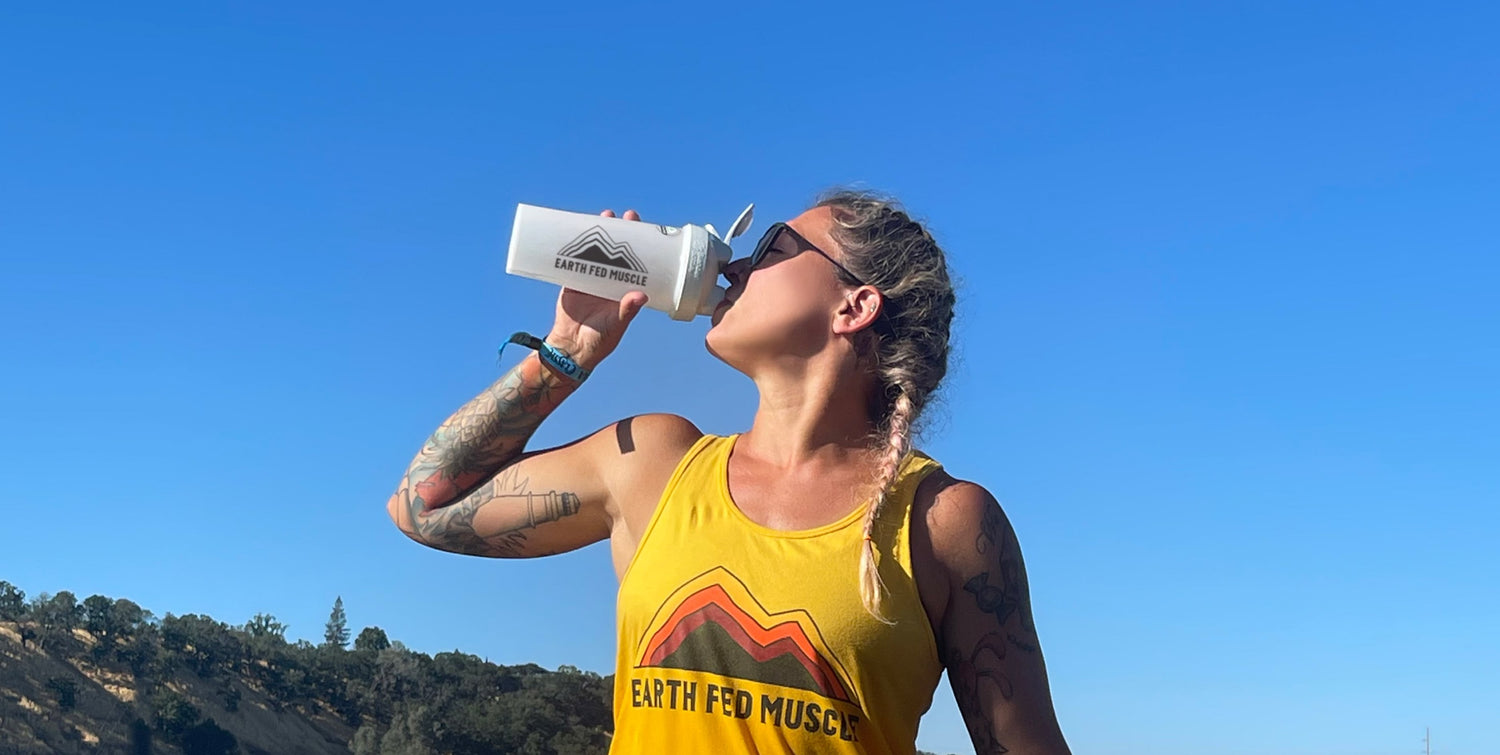 Woman drinking protein shake in front of sky and mountain