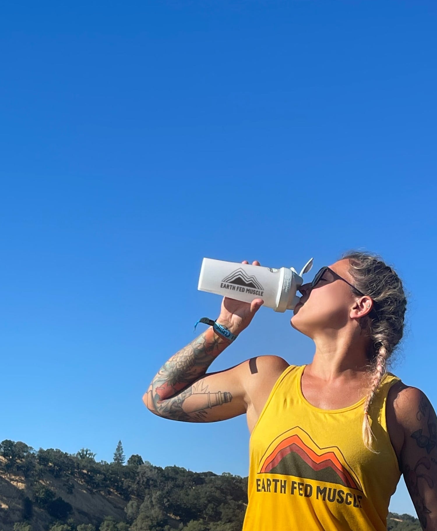 Woman drinking protein shake in front of sky and mountain