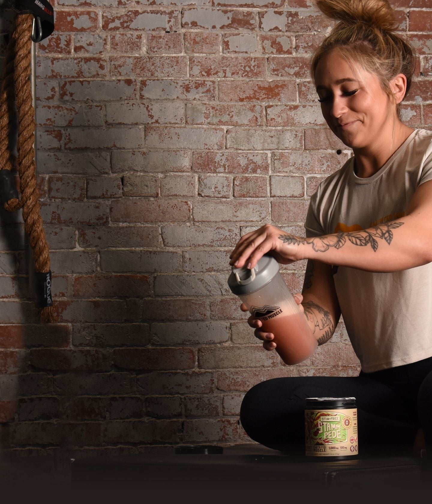 Girl mixing stimulant free Stammpede sour cherry pre-workout in a shaker bottle, portrait orientation